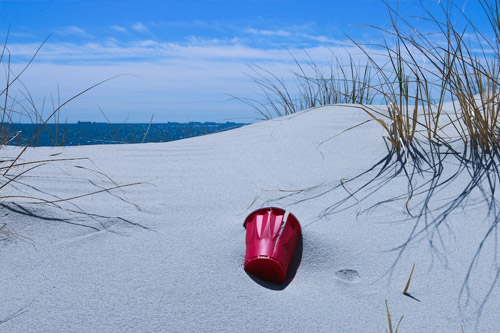Embracing Sustainable Living: red plastic cup in a sand dune during a beach clean